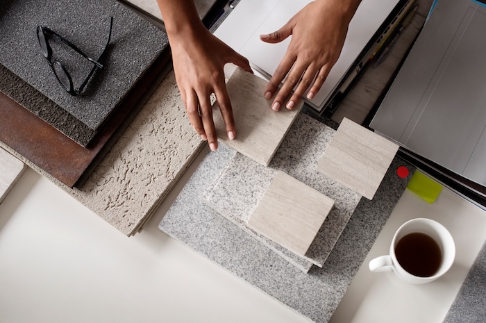 Overhead view of interior designer examining tiles at desk in office